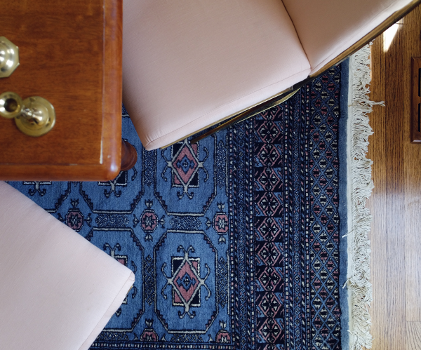 Vintage blue and pink rug under dining room table. Pink PIerre Cardin brass chairs give a Hollywood Regency look and feel. The vintage farm table tones down the glam.