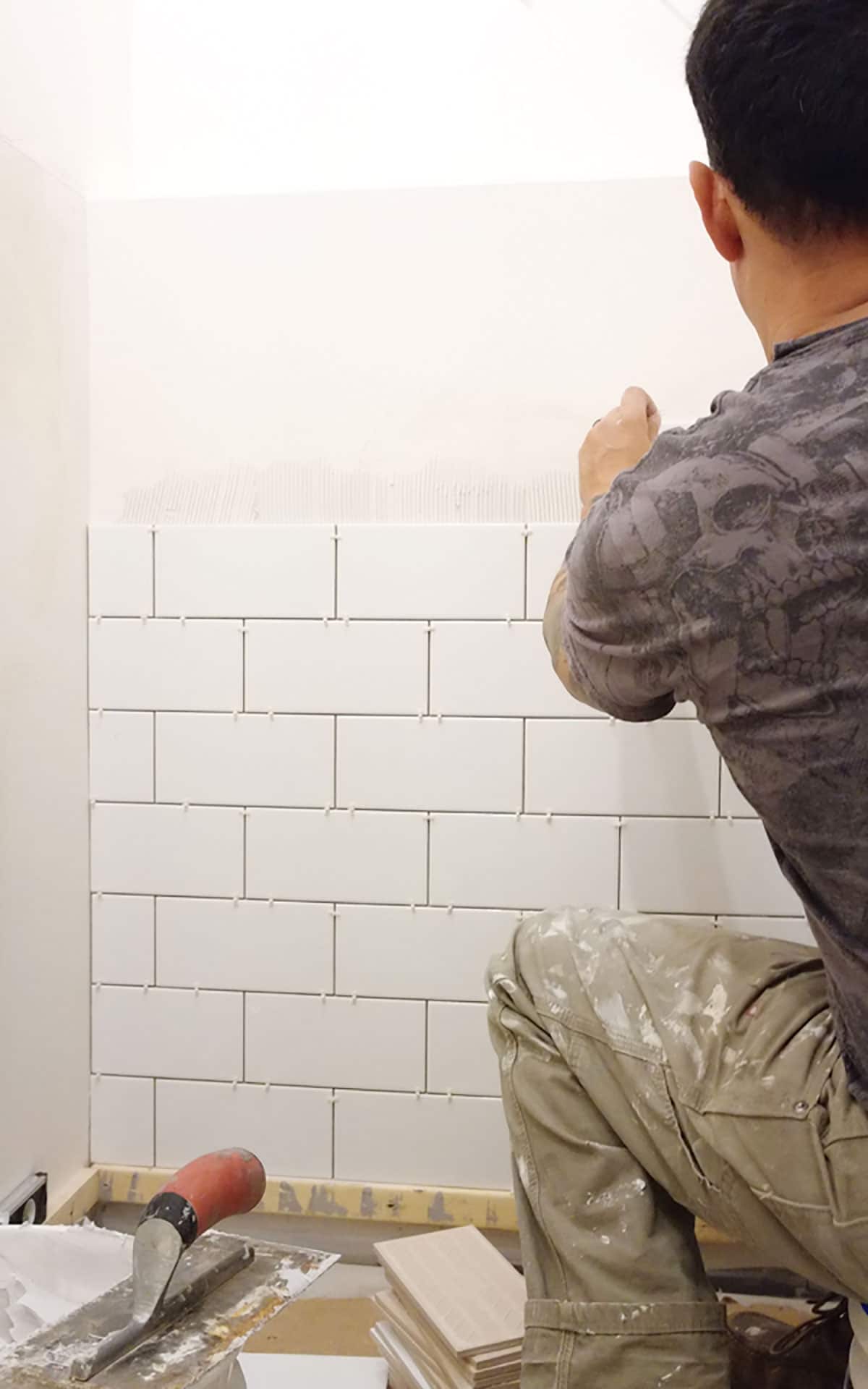 Laying the white subway tile in the bathroom renovation