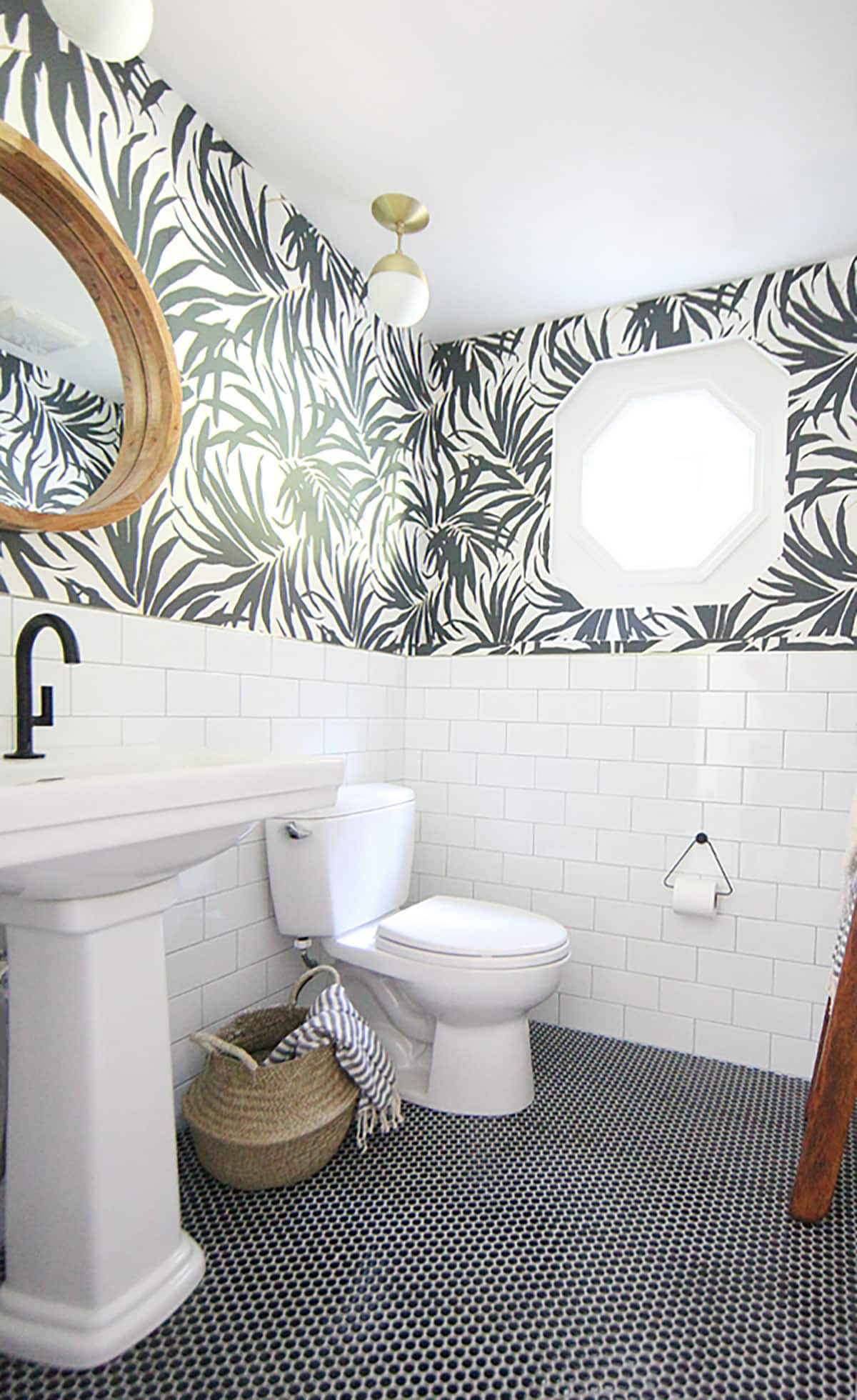 Black and white modern bathroom will palm tree peel and stick wallpaper black penny tile and white subway tile. 