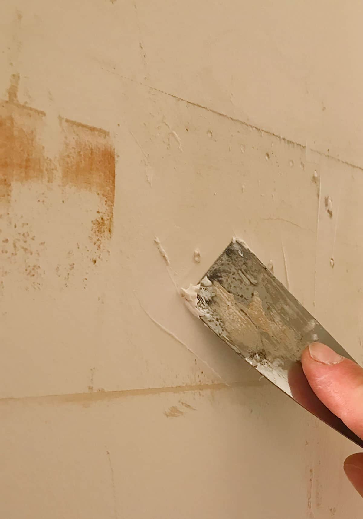 repair the drywall with spackle before hanging your wallpaper for a smooth surface