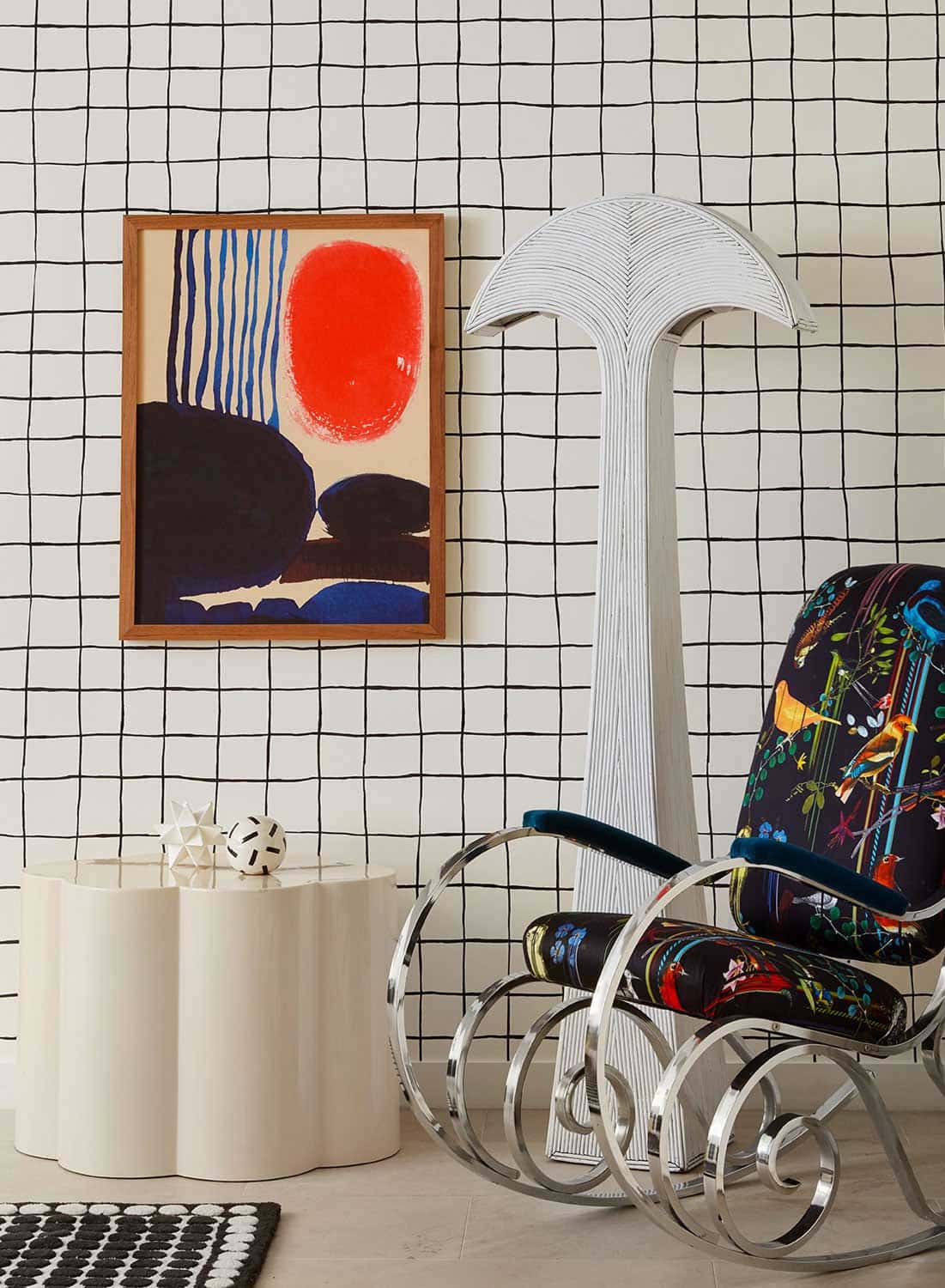 Graphic black and white grid pattern wallpaper in kids playroom with colorful art and vintage rocking chair