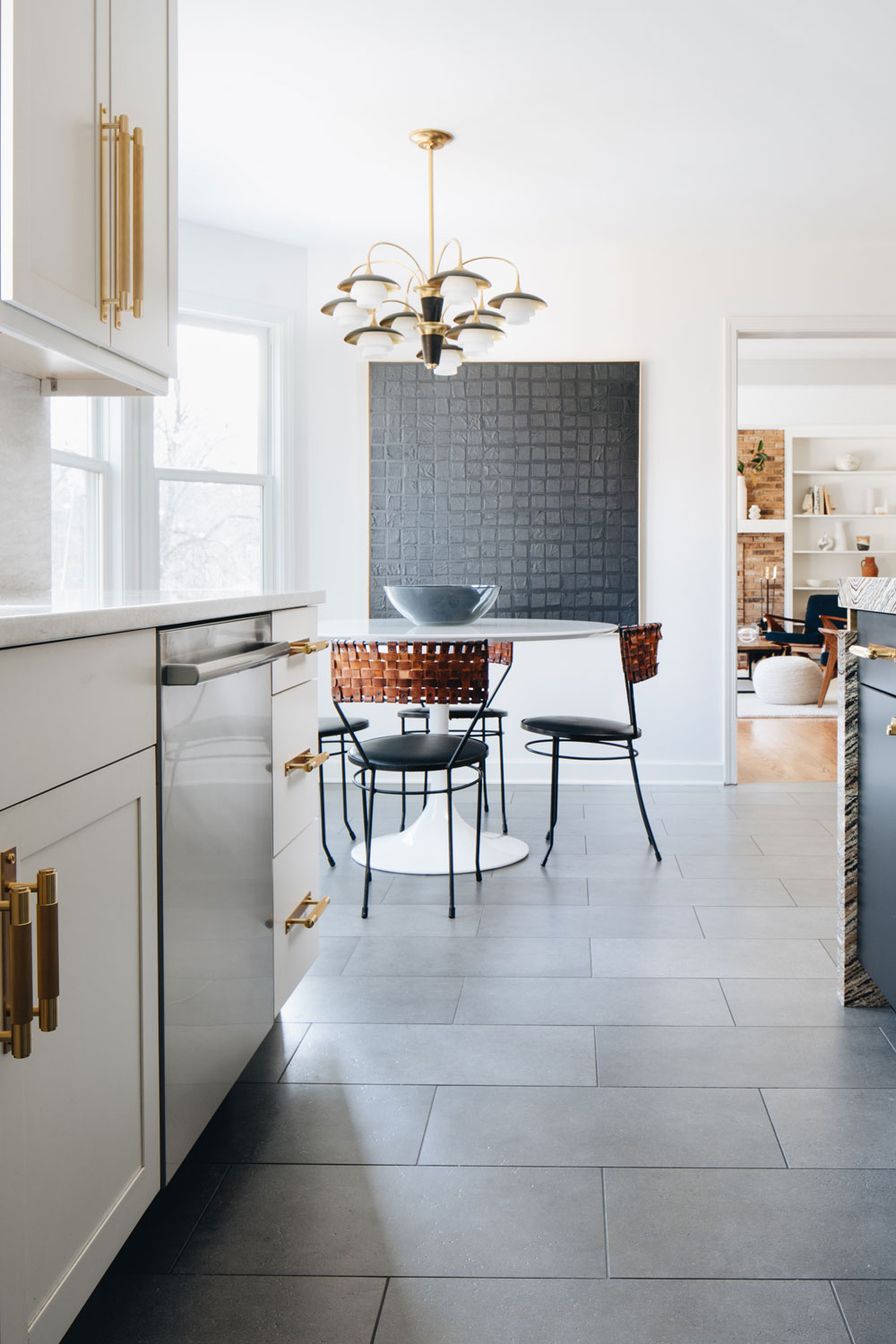 Modern Kitchen Makeover Renovation On A Budget - Art Deco inspired chandelier over mid-century modern white tulip table. Paired with vintage Arthur Umanoff woven leather back dining chairs. Art by Kelly Caldwell. 