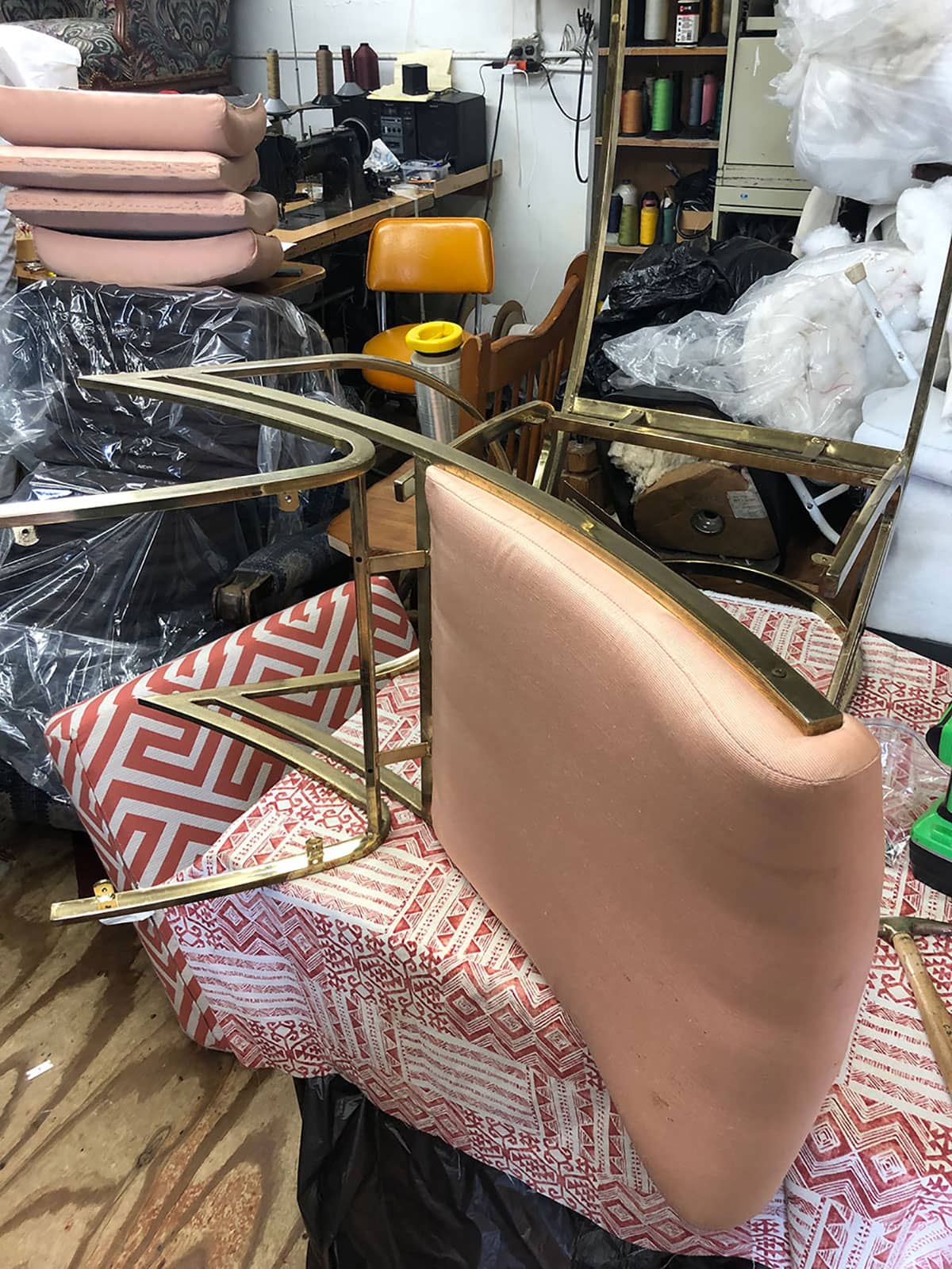 Original brass cantilever chairs in pink by Pierre Cardin at the upholstery shop, ready to be covered in Ultrasuede performance fabric in green