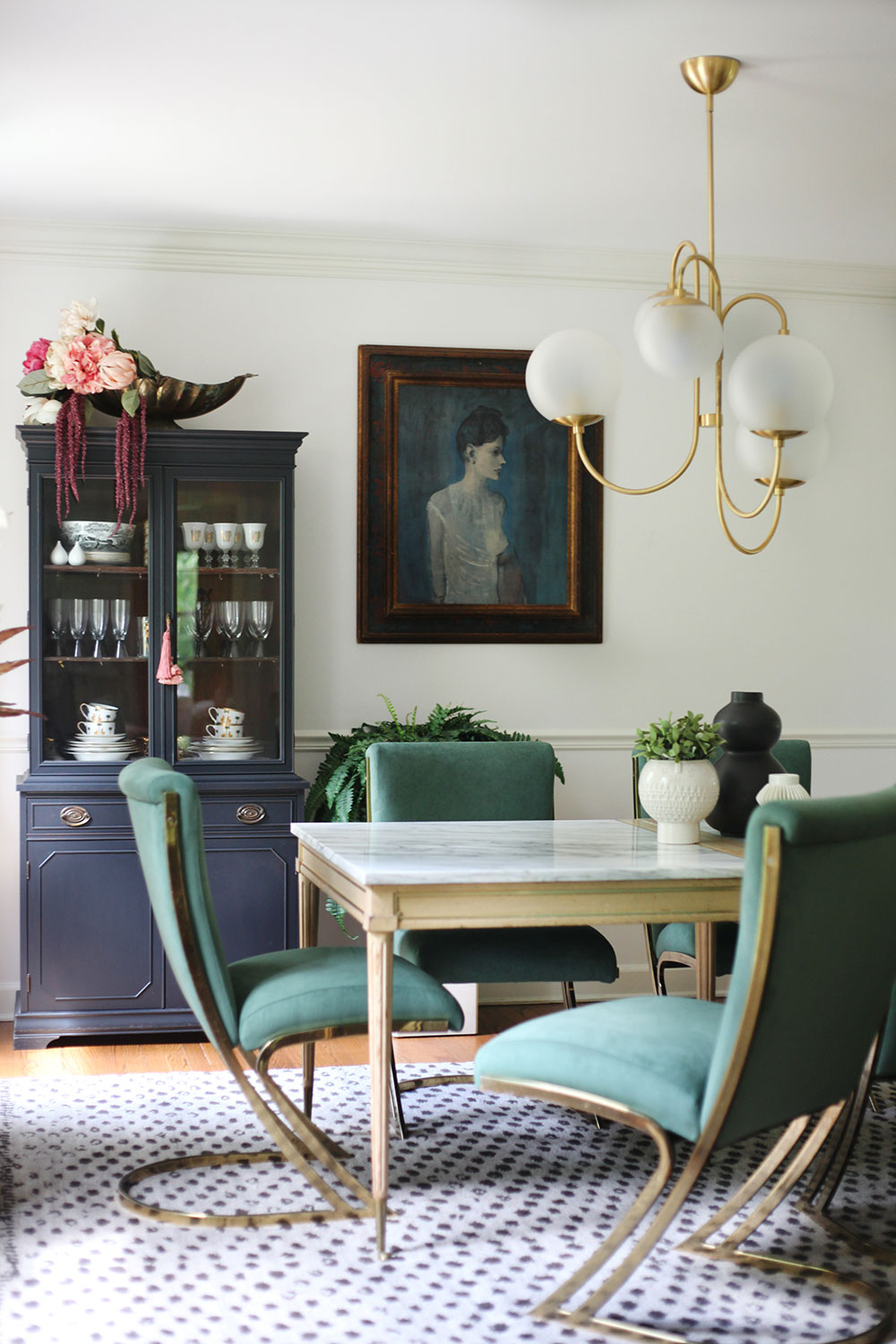 Reupholstered dining chairs in green and brass cantilever chairs by Pierre Cardin in eclectic modern dining room. Modern chandelier and 1950s French marble pastry table used as dining table. Mixing vintage with new.