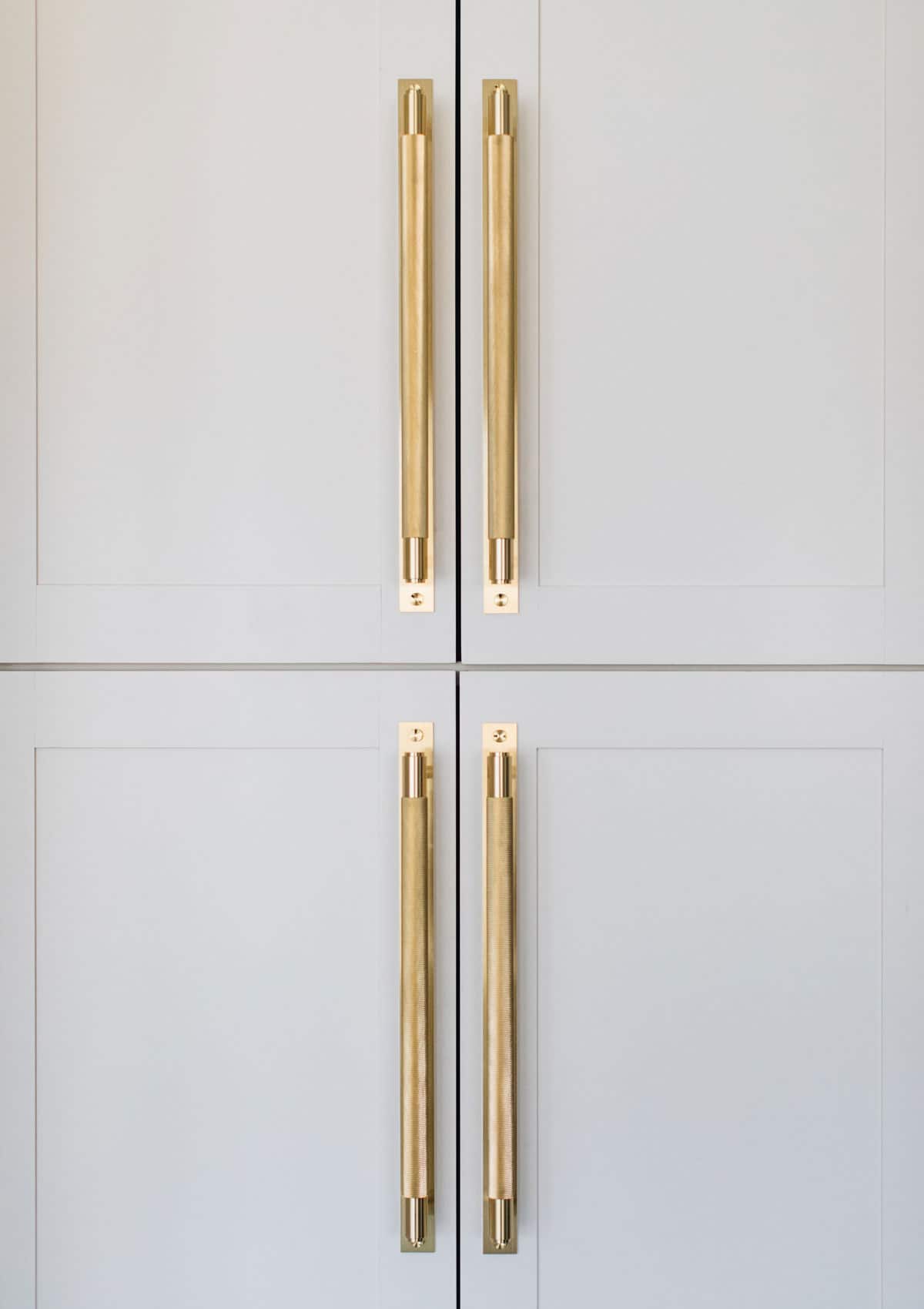White Kitchens Are Not Out Here are 7 Ideas to Warm Them Up - Luxe brass hardware warms these white kitchen cabinets