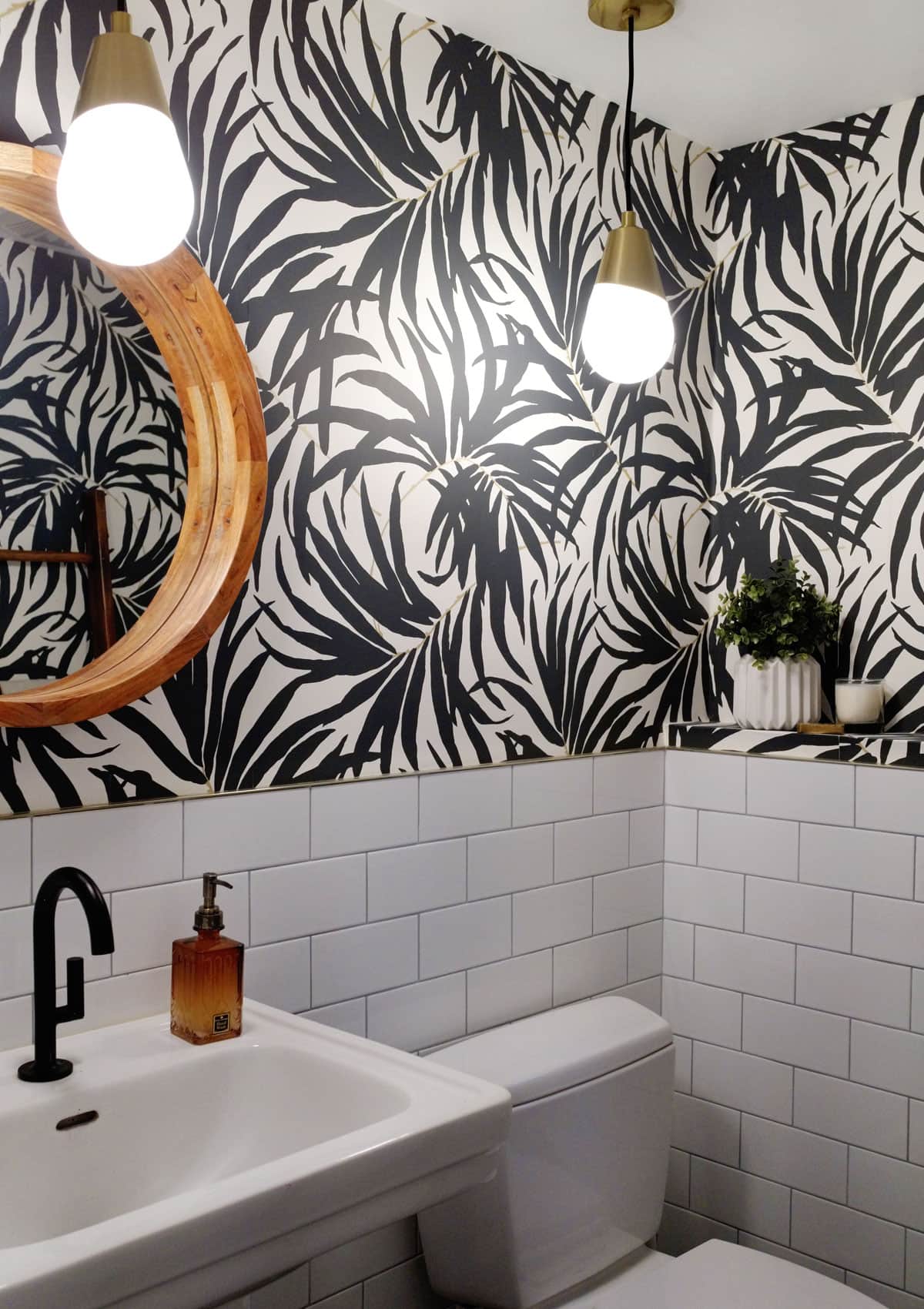 Black and White Bathroom Renovation Before and After - Transforming an old, outdated, boring bathroom and creating a stunning modern black and white bathroom with palm frond wallpaper and subway tile.